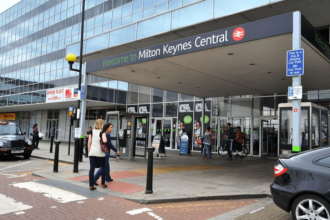 Police officers at Milton Keynes railway station cordon off area following a fatal shooting incident involving an armed suspect.