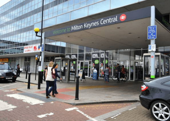 Police officers at Milton Keynes railway station cordon off area following a fatal shooting incident involving an armed suspect.