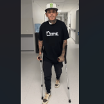 Tai Woffinden walking with crutches in a hospital corridor, starting rehabilitation following his speedway crash in Poland.